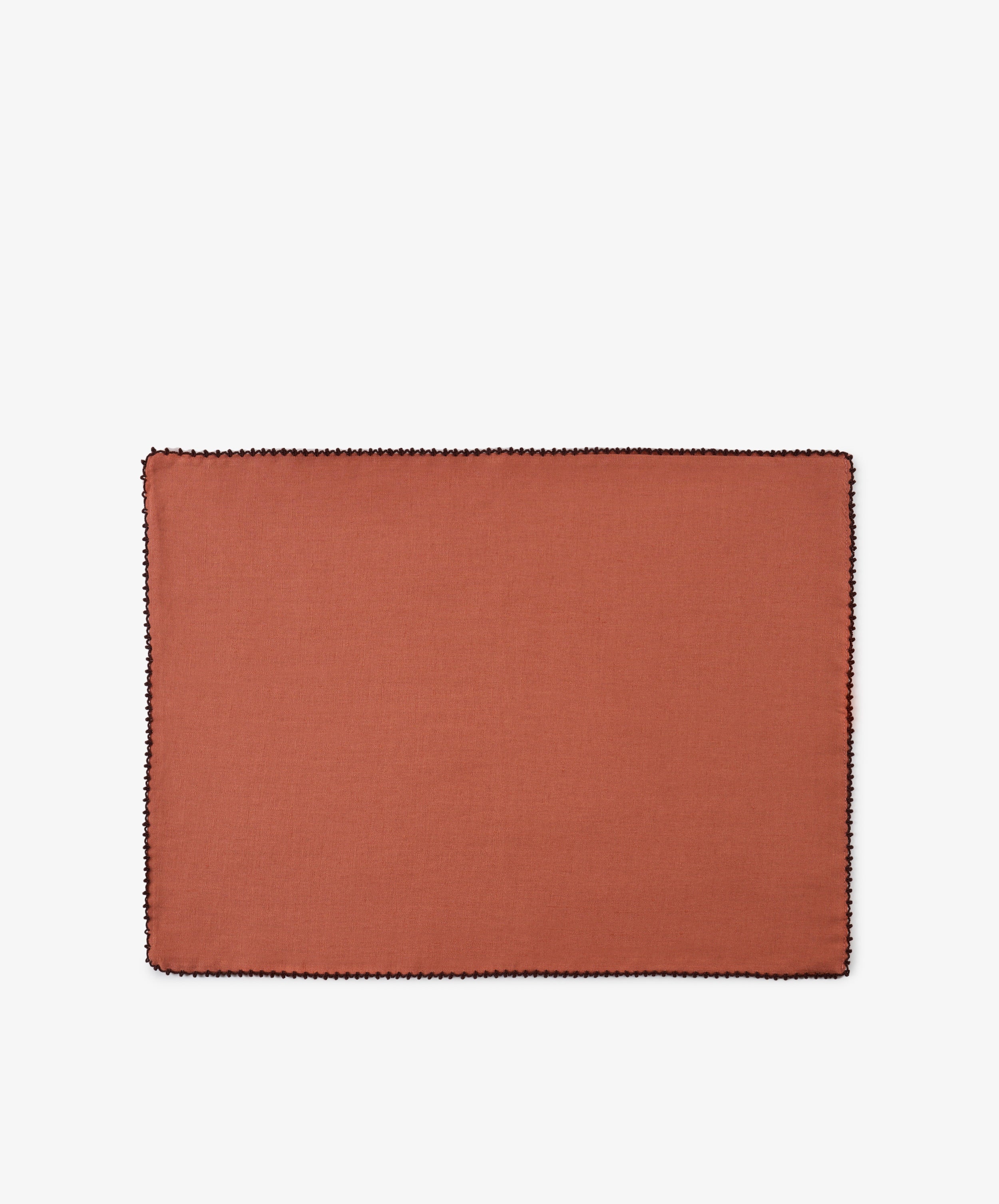 A set of six Nico Placemats, each rectangular and crafted from rust-colored linen with a black stitched border, is displayed on a plain white background, highlighting the quality and style of these handmade Portuguese placemats.
