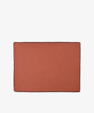 A set of six Nico Placemats, each rectangular and crafted from rust-colored linen with a black stitched border, is displayed on a plain white background, highlighting the quality and style of these handmade Portuguese placemats.