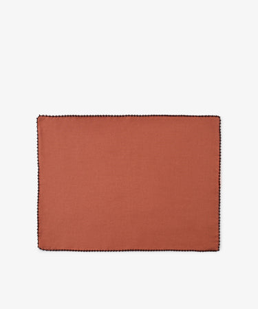 A set of six Nico Placemats, each rectangular and crafted from rust-colored linen with a black stitched border, is displayed on a plain white background, highlighting the quality and style of these handmade Portuguese placemats.