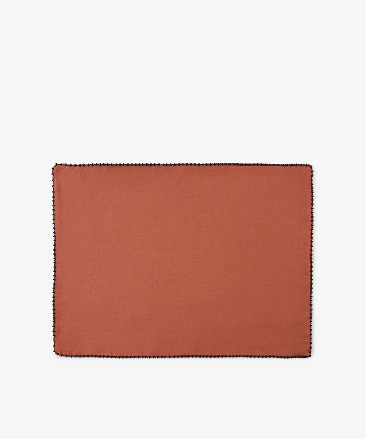 A set of six Nico Placemats, each rectangular and crafted from rust-colored linen with a black stitched border, is displayed on a plain white background, highlighting the quality and style of these handmade Portuguese placemats.