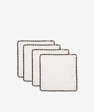 The Nico Cocktail Napkin set features four white hand-finished napkins with dark contrast stitching and scalloped edges, arranged in a staggered stack against a plain white background.