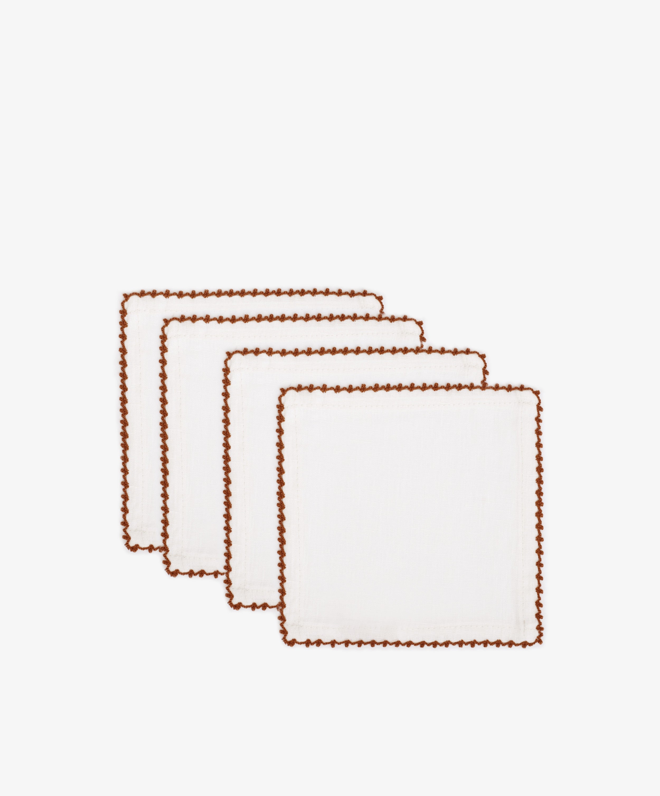 Set of 4 Nico Cocktail Napkins in white, each with brown contrast stitching on the edges, hand-finished and displayed in a staggered row on a white background.