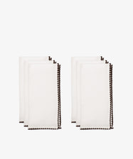 The Nico Napkin, Set of 6, features white cloth napkins with dark scalloped edges, neatly folded and arranged in two stacksâ€”perfect for enhancing any table setting.