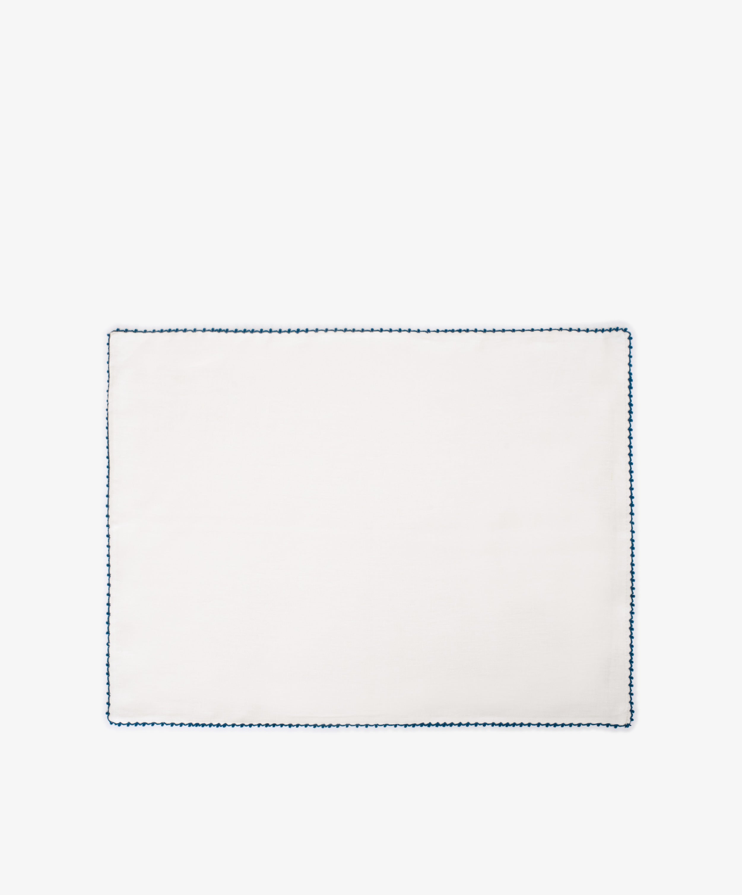 The Nico Placemat, Set of 6, features plain white linen with a blue hand-stitched edge—perfect for adding elegant table decor to any setting. Photographed on a white background.