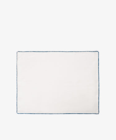 The Nico Placemat, Set of 6, features plain white linen with a blue hand-stitched edge—perfect for adding elegant table decor to any setting. Photographed on a white background.