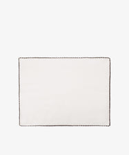 The Nico Placemat, Set of 6, features rectangular white linen with a dark hand-stitched edge, displayed on a plain white backgroundâ€”ideal for bringing Italian elegance to your table.