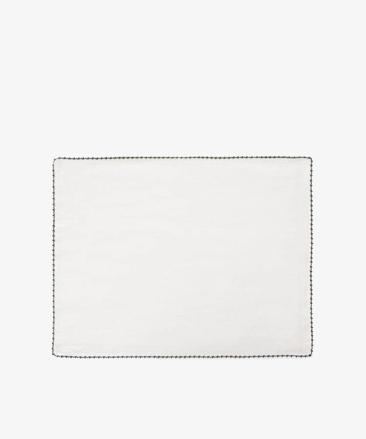 The Nico Placemat, Set of 6, features rectangular white linen with a black hand-stitched edge, shown on a white backgroundâ€”ideal for adding Italian elegance to your table.