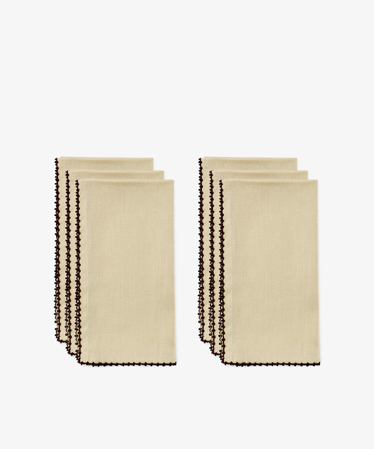 Four folded beige hand-finished napkins with dark espresso contrast stitch along the edges, arranged in two groups of two, on a white background.
