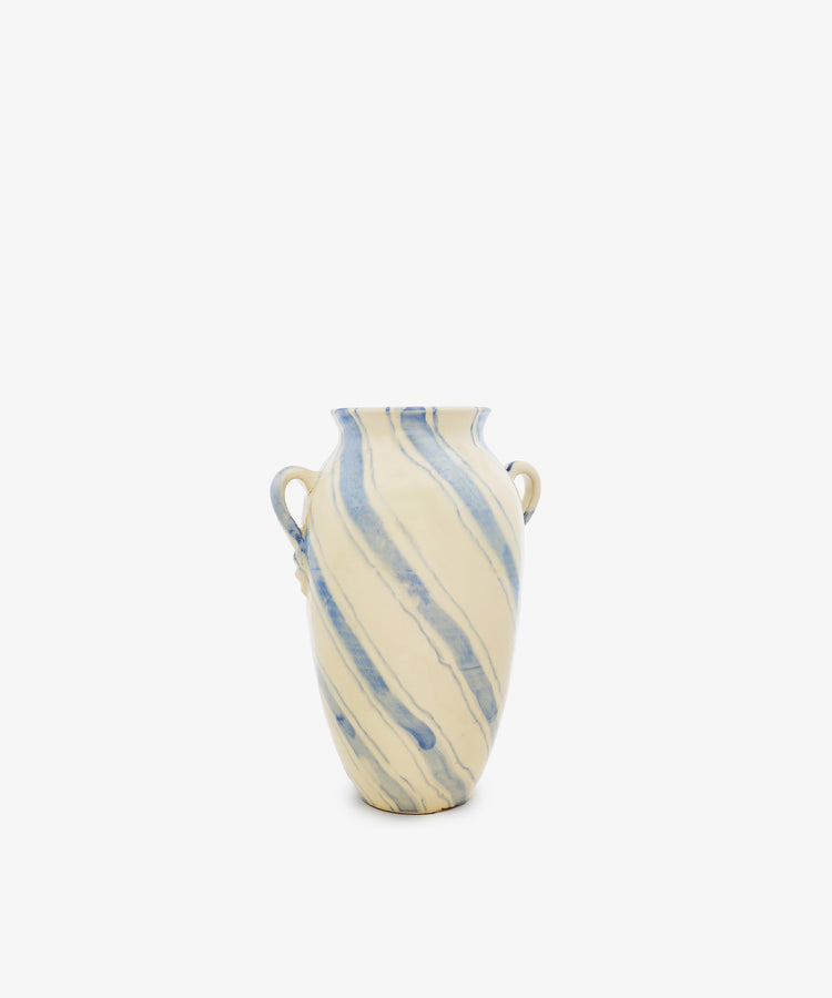 The Ida Vase features an amphora-shaped ceramic silhouette with two small side handles, showcasing a cream base color embellished with hand-painted blue diagonal marbled stripes, all set against a plain white background.