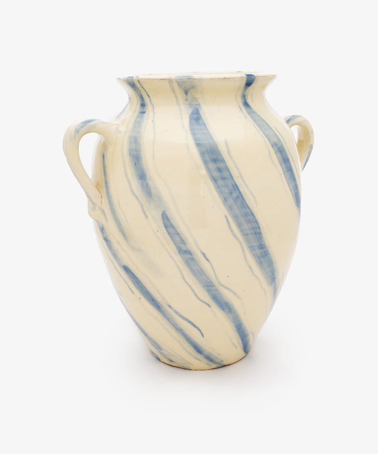 The Ida Vase is a cream-colored ceramic amphora with two handles and blue diagonal stripes, displayed on a plain white background.