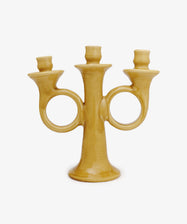The Loretta Candelabra is a yellow ceramic, handmade, hand-shaped piece with three candle holders and two circular handles, exuding Old World charm against a plain white background.