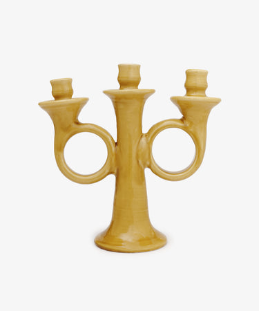 The Loretta Candelabra is a yellow ceramic, handmade, hand-shaped piece with three candle holders and two circular handles, exuding Old World charm against a plain white background.