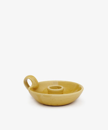 The Balea Candleholder is a yellow ceramic chamberstick with Old World charm, featuring a round base, central candle holder, and side loop handle, shown on a plain white background.