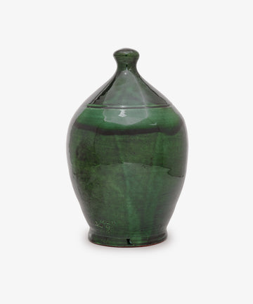 The Hugo Money Pot is a handcrafted green ceramic coin bank with a rounded body, slightly pointed top, glossy finish, and fitted lid—perfect for decorative use.