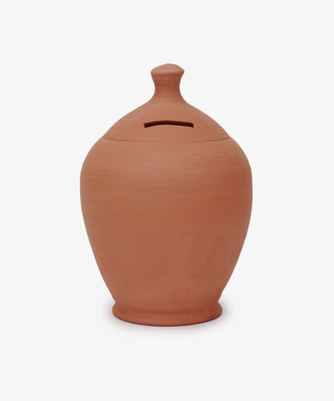The Hugo Money Pot is a sculptural terracotta clay coin bank with a rounded body, small knob lid, and a horizontal slot for inserting coins.
