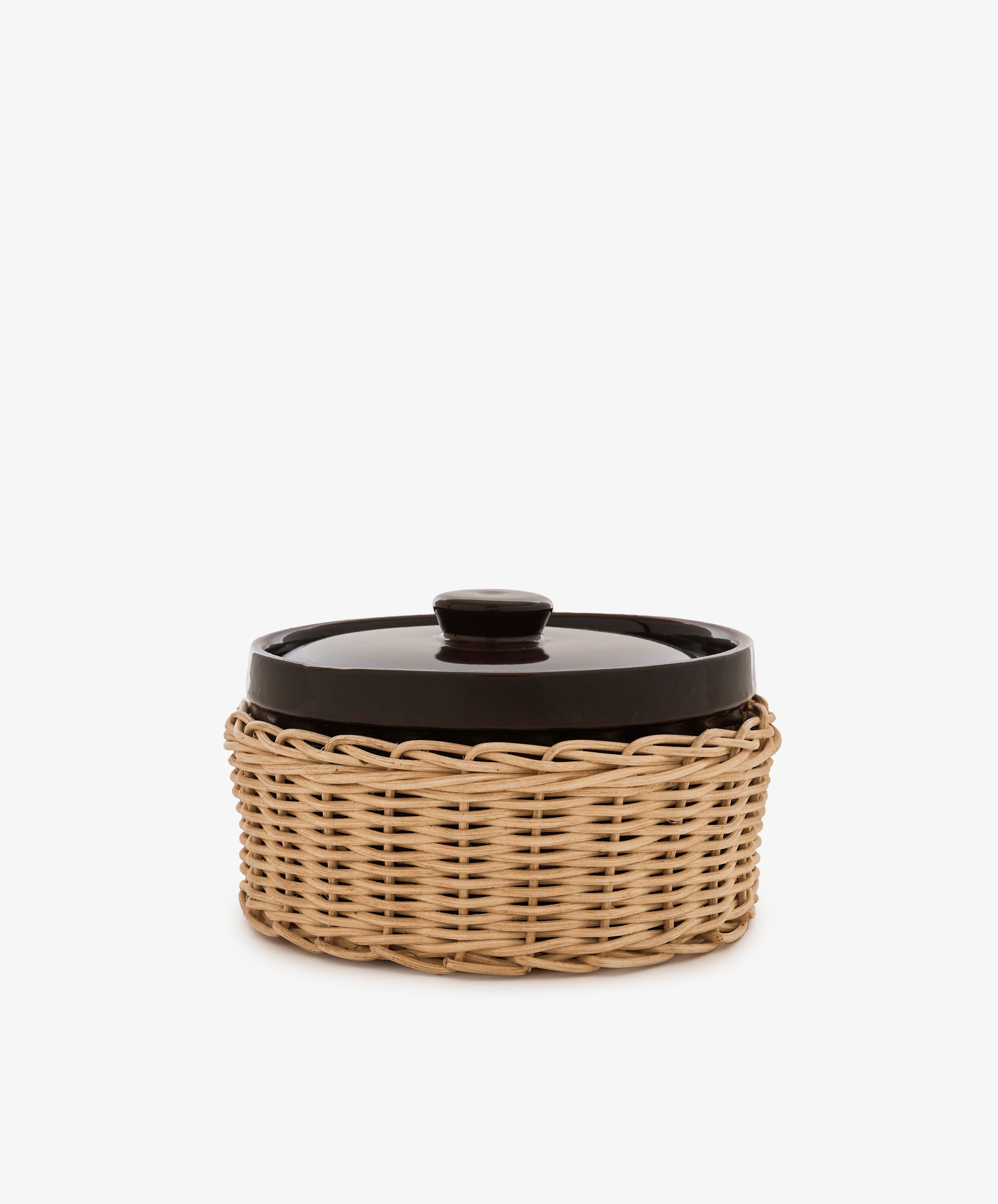 Amany Casserole, a black-lidded ceramic baking dish nestled in a round woven rattan basket, photographed against a plain white background.