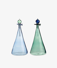 The Duo Vinegar & Oil Flask set features two tall, conical glass bottles—one light blue and one green—with stoppers, crafted in a Cairo artisan style to add an elegant, hand-blown touch to your home décor.