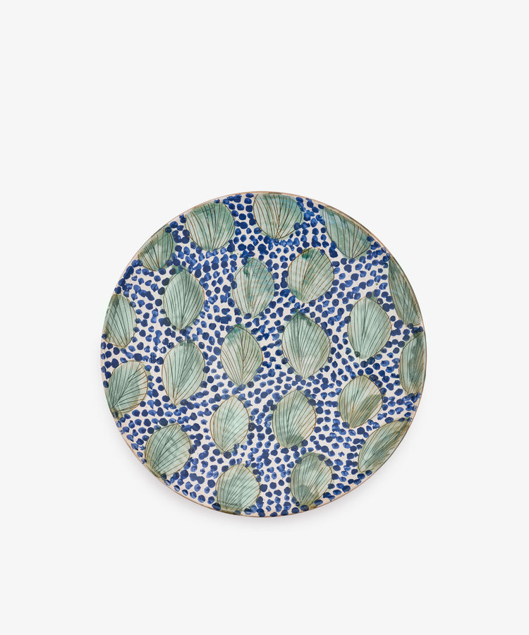 Green Leaves Serving Bowl inspired by Fayoum pottery, featuring a pattern of green leaves and blue dots on a white background, viewed from above against a plain white surface.
