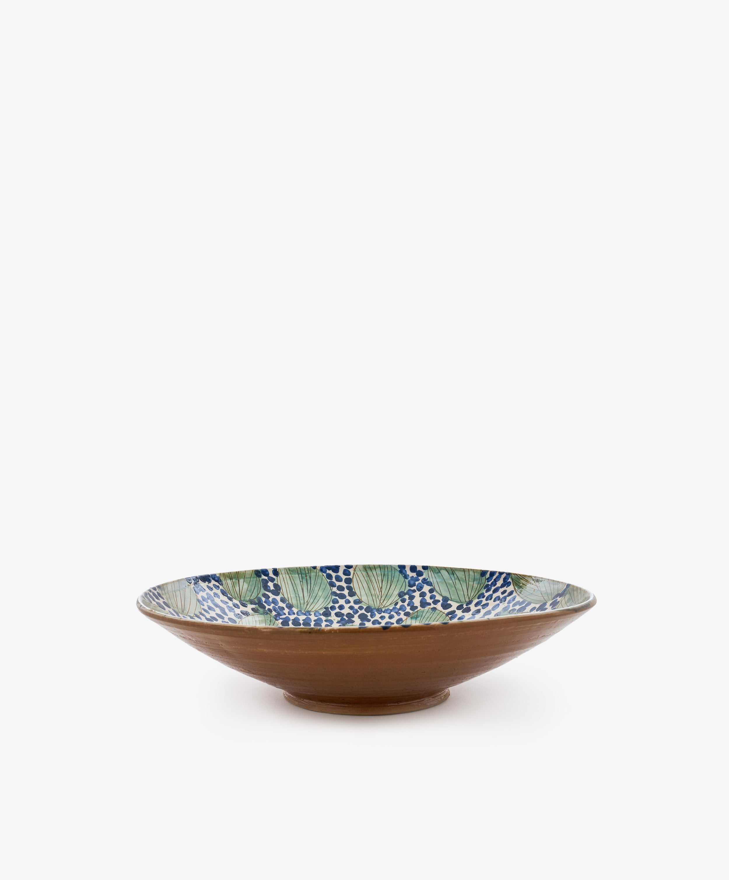 The Green Leaves Serving Bowl is a wide, shallow handmade bowl featuring a brown exterior and an interior adorned with green leaves and a blue dot pattern on a white background, inspired by traditional Fayoum pottery.