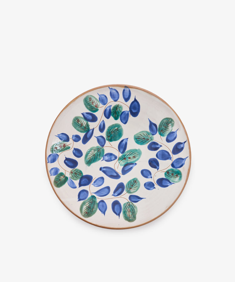 Midnight Garden Serving Bowl crafted from ceramic, featuring a beige background and adorned with a hand-painted design of green leaves and blue oval-shaped fruits inspired by traditional Fayoum pottery.