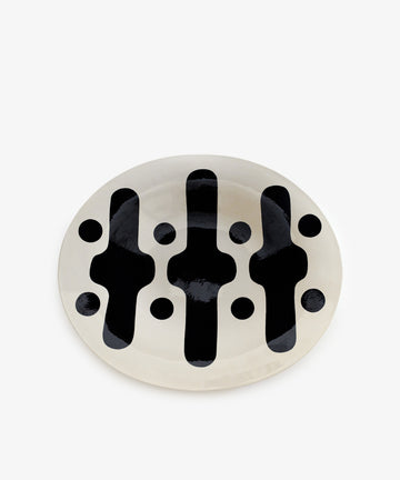 Motif 1, Oval is an oval ceramic plate with a white base and bold black abstract patterns and dots, inspired by geometric modernism—perfect for enhancing any decorative platter collection.