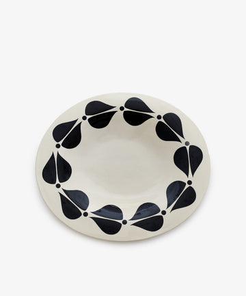 The Motif 4, Oval is a handcrafted white ceramic plate with black teardrop shapes circling the rim, ideal as a decorative platter or for serving.