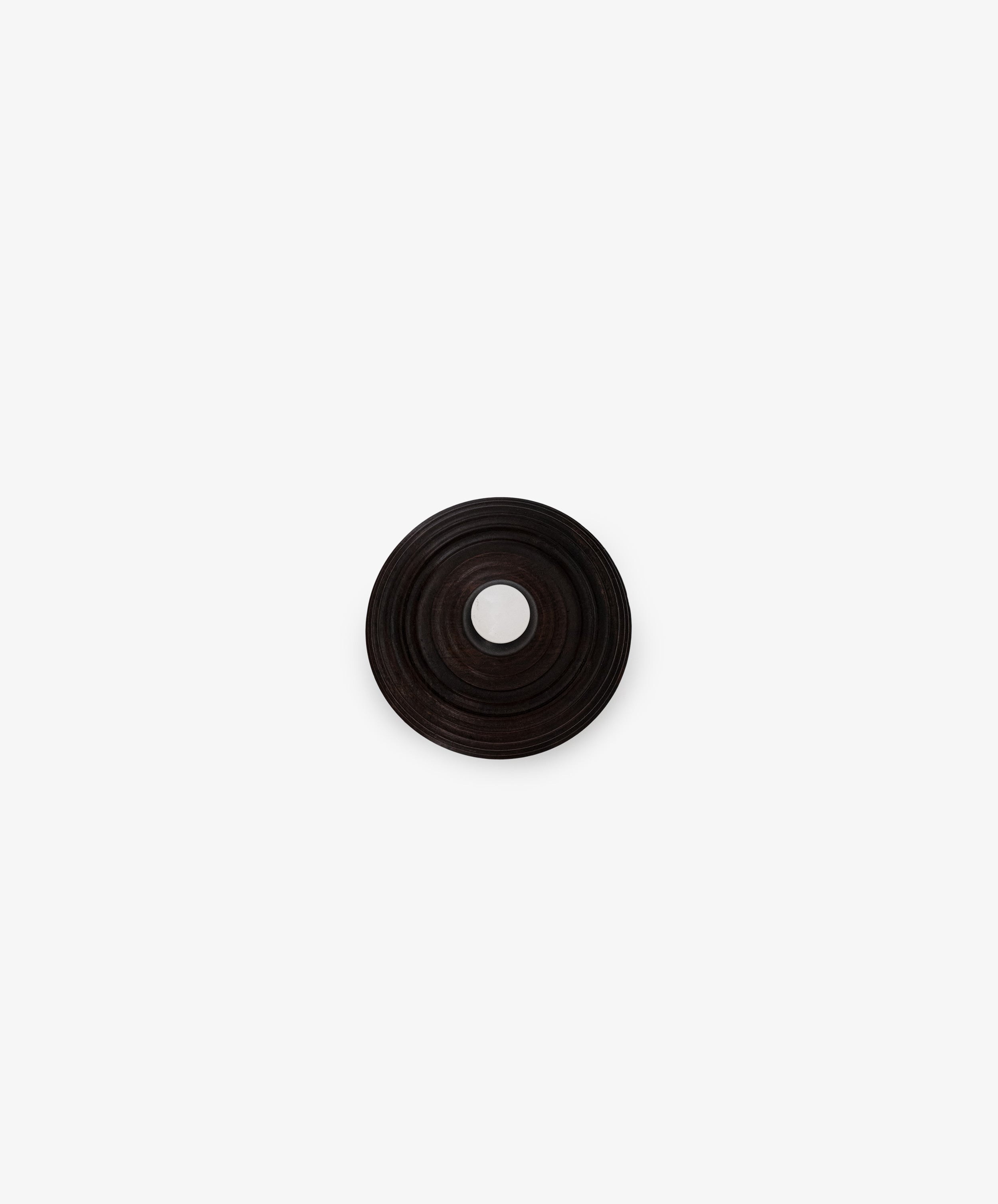 The Curiosity Box is a dark, circular African wood box with concentric ridges and a central hole, shown from above on a plain white background.