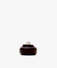 The Curiosity Box, a round African wood keepsake with a small knob on top, is displayed against a plain white background.