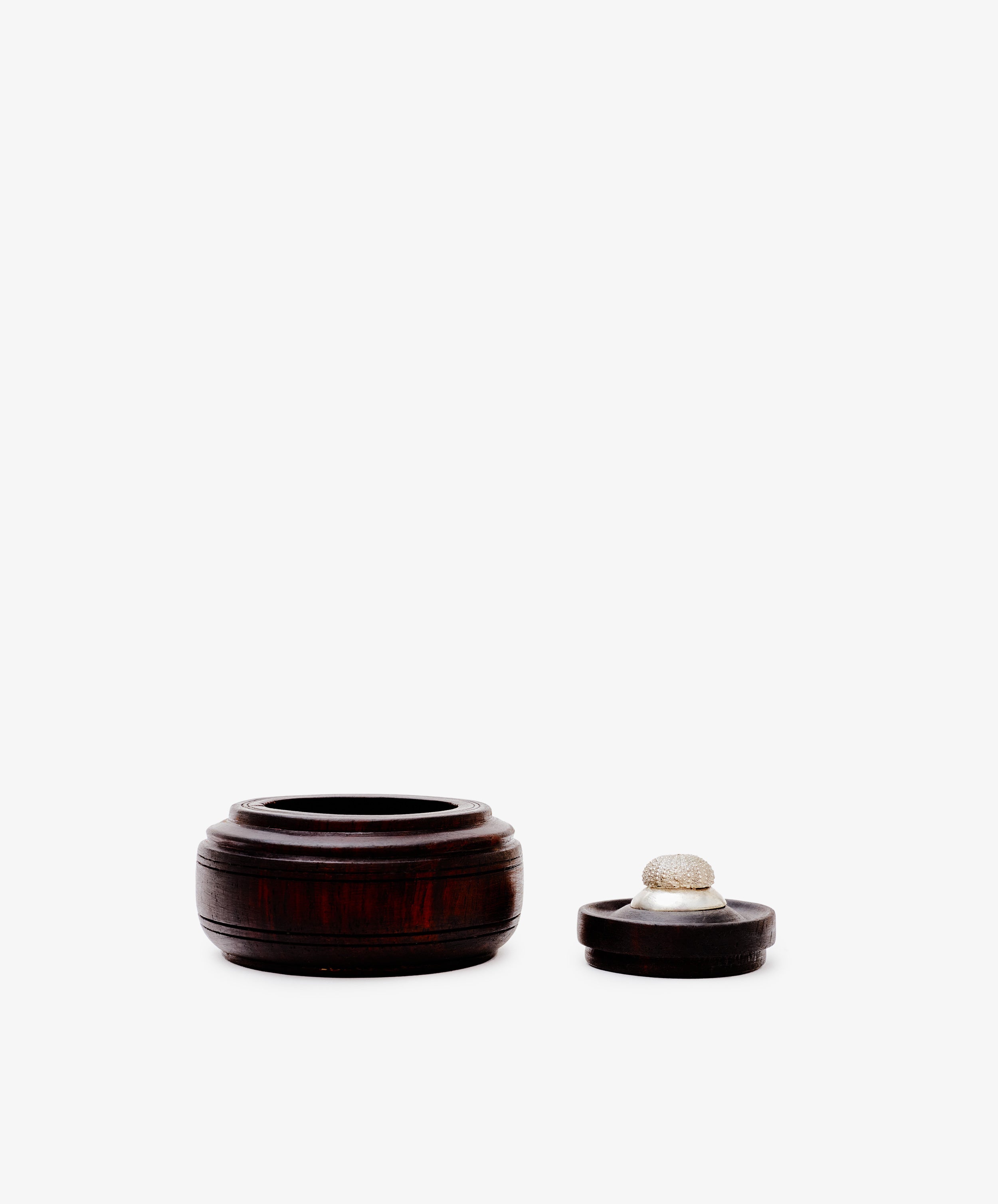 The Curiosity Box, a small round African wood box with its lid beside it on a plain white background, makes a perfect collectible keepsake for any decor.