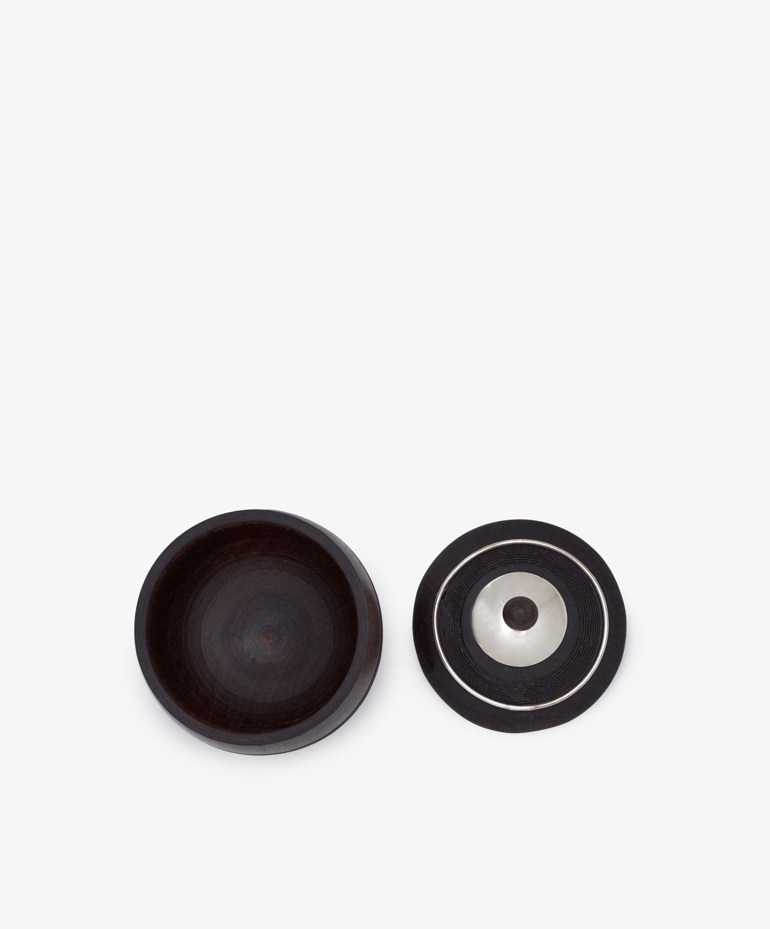 Curiosity Box 17: A round, dark-toned African wood box with a matching lid featuring concentric circles and a metallic center, showcased on a white background.