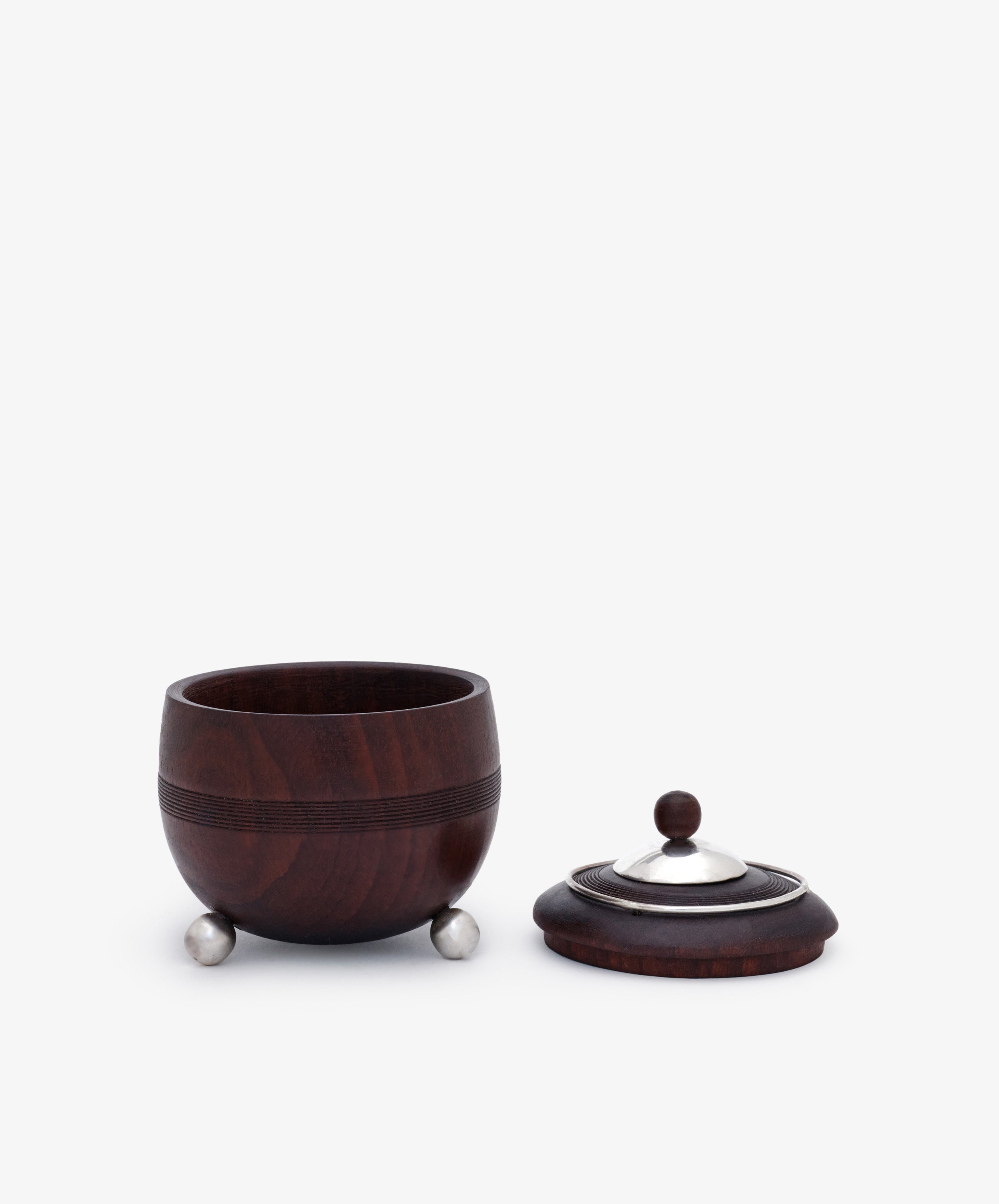 Curiosity Box 17: A small, round African wood box with metal feet and a matching lid featuring a metal knob, shown with the lid beside the container—an elegant piece from the Antje Weber collection.
