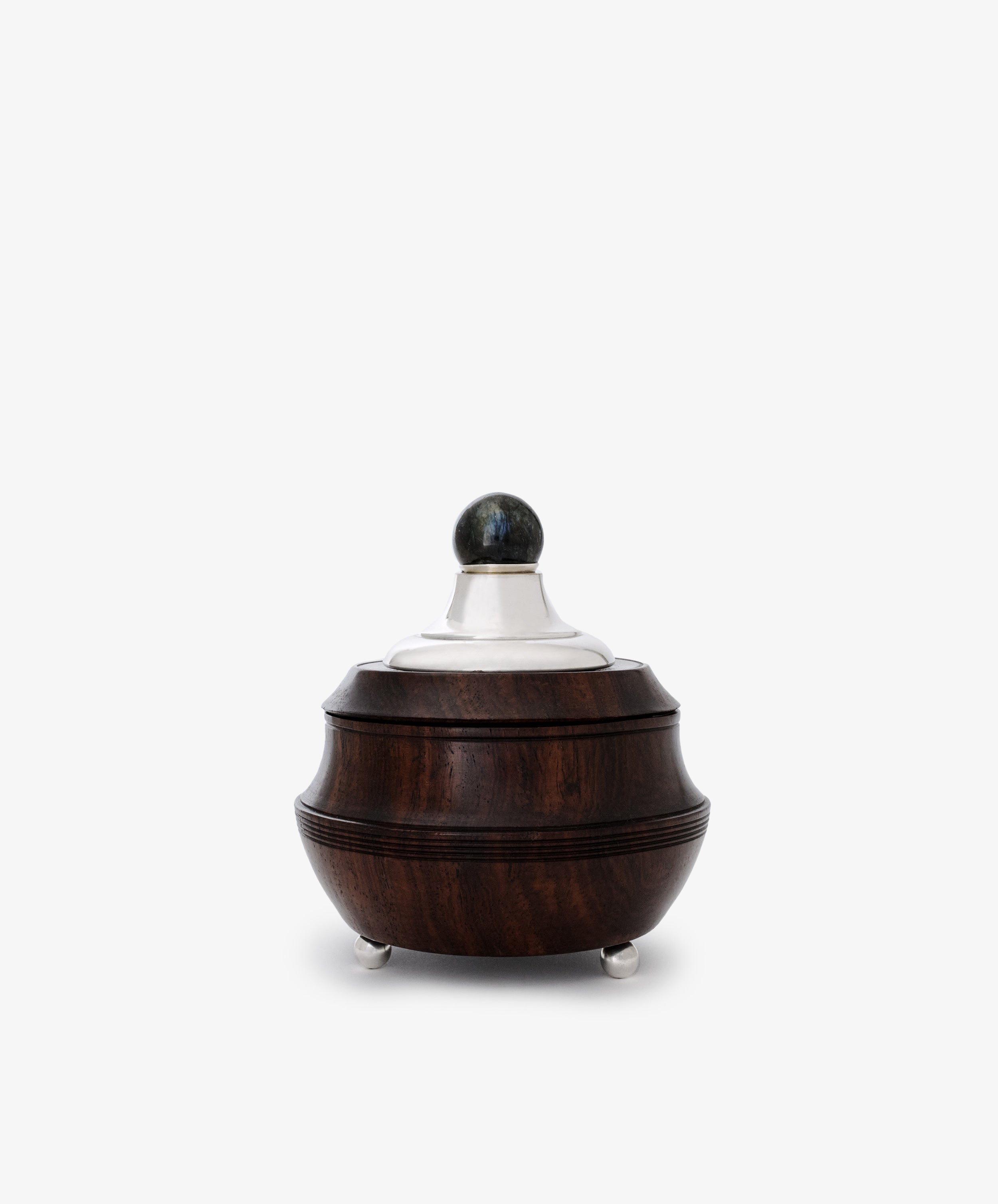 The Curiosity Box is a restored vintage round container crafted from dark African wood with sterling silver accents—a silver lid, spherical knob, and three elegant feet—shown against a plain white background.