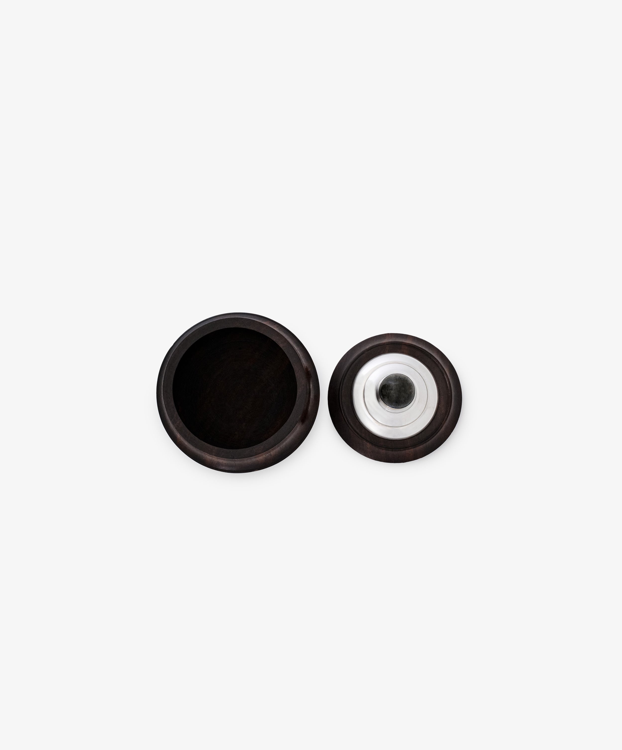 The Curiosity Box is a round, dark African wood box shown open with its lid beside it, revealing sterling silver accents on the metal insert beneath the lid.
