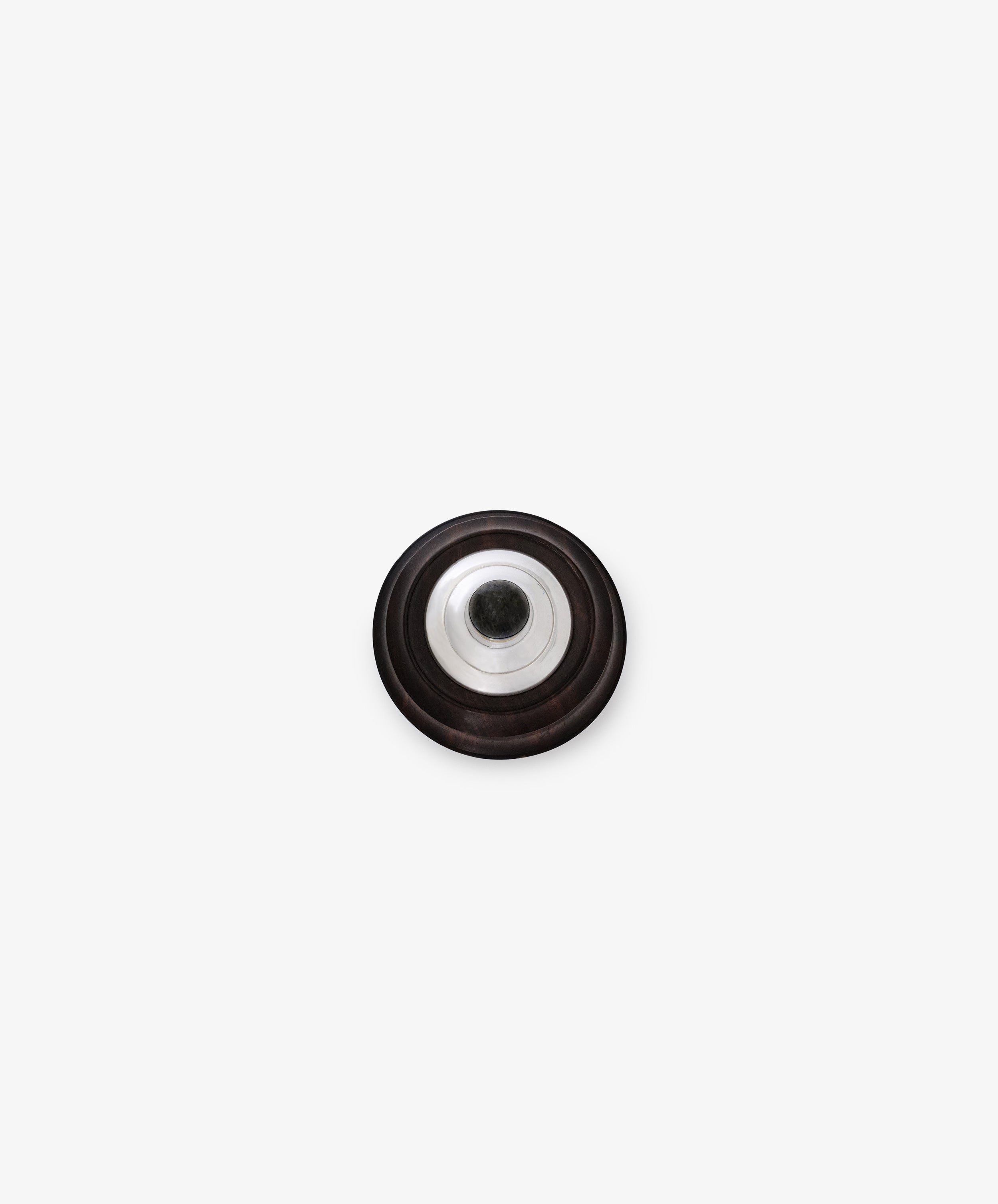The Curiosity Box is a round, black metallic disc with sterling silver accents and a central hole, shown from above on a plain white background.