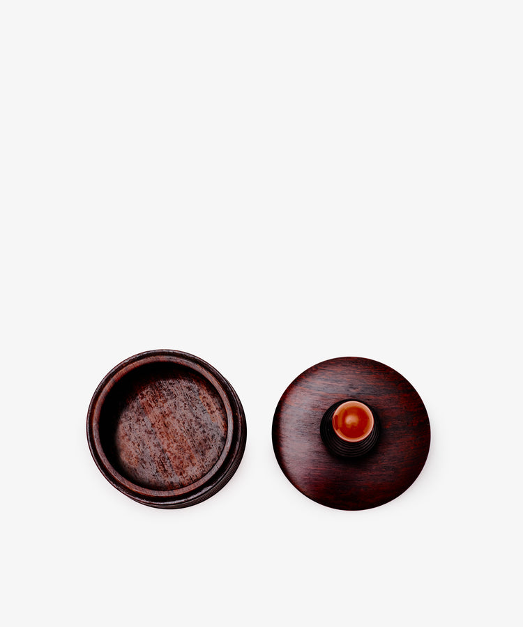 The Curiosity Box, a round African wood container with its matching lid, sits on a plain white background.
