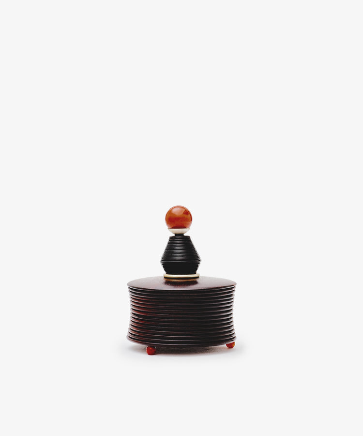 The Curiosity Box is a small, round African wood box with ridged sides, a lid, and an orange knob handle—a charming vintage keepsake for your treasured items.
