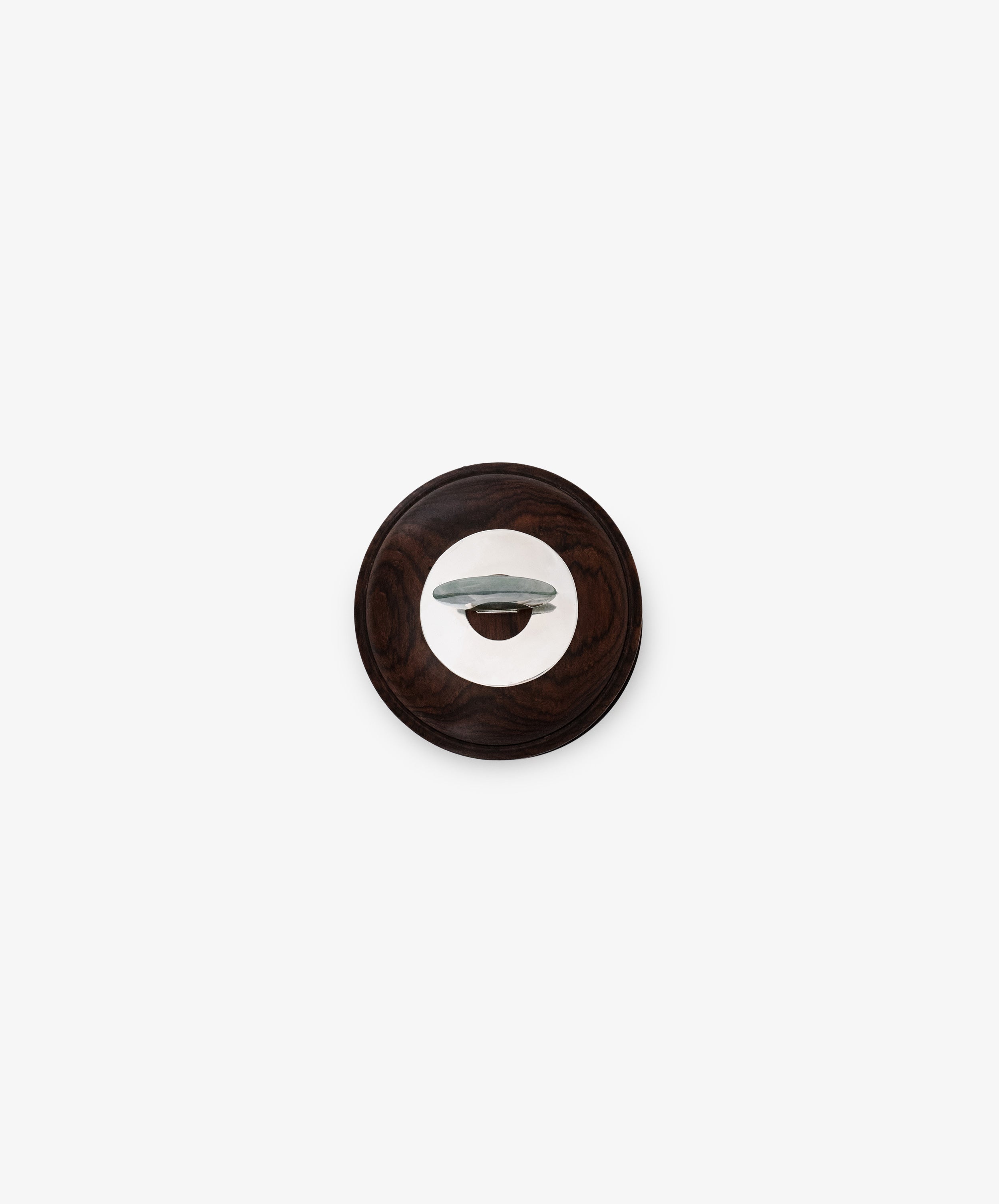 The Curiosity Box, a round wooden object with a central metal handle, is centered on a plain white background, resembling a classic door or cabinet knob.