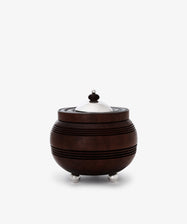 The Curiosity Box is a round African wood box with horizontal grooves, featuring a silver metal lid, knob, and three small silver feet—an artisan keepsake that stands out beautifully against a white background.