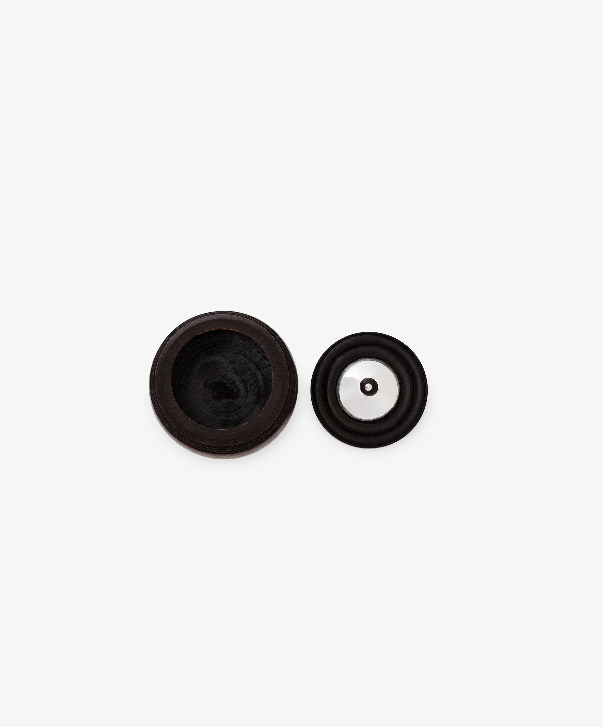 Two round black rubber objects with central holes, one larger than the other, are placed side by side on a white background, resembling minimalist accents that complement the Curiosity Box.