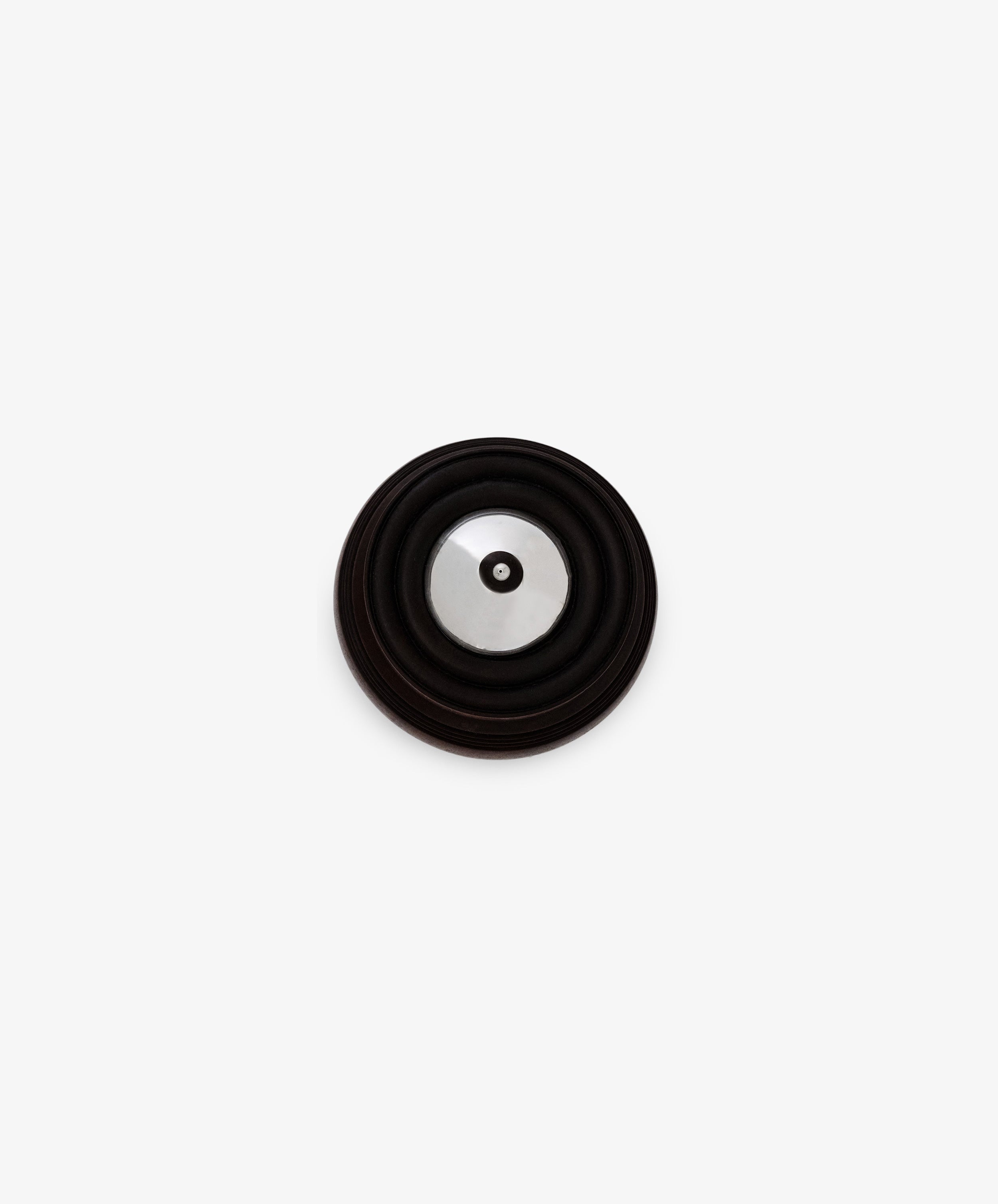 The Curiosity Box, a round metallic object with a black circular rim, sits centered on a white background—its design reminiscent of an artisan keepsake box and evoking a sense of timeless appeal.