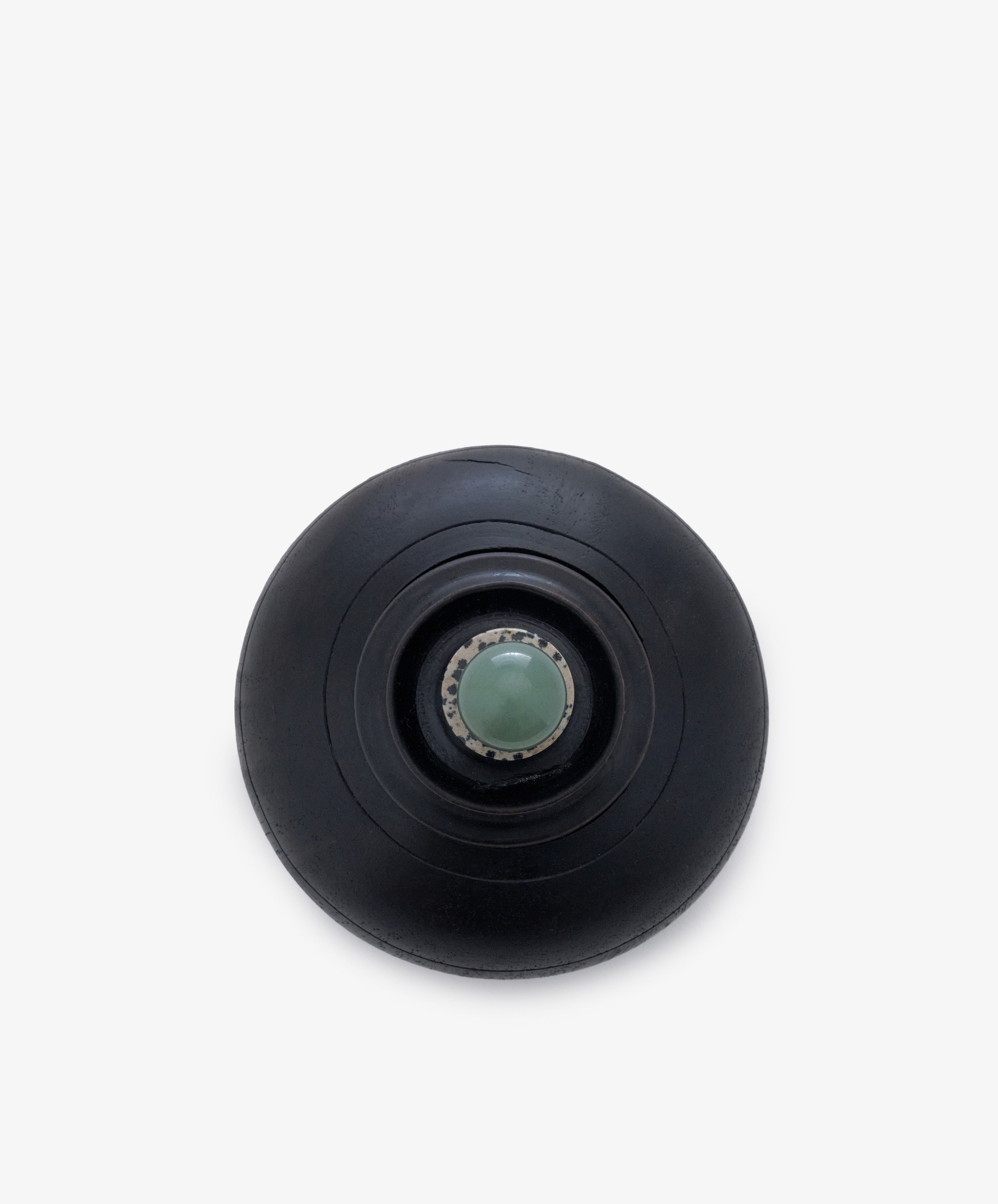 Curiosity Box 2: A black circular keepsake box with concentric rings and a central metallic accent holding a greenish sphere, shown from above on a white background.