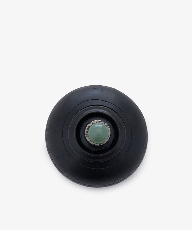 Curiosity Box 2: A black circular keepsake box with concentric rings and a central metallic accent holding a greenish sphere, shown from above on a white background.