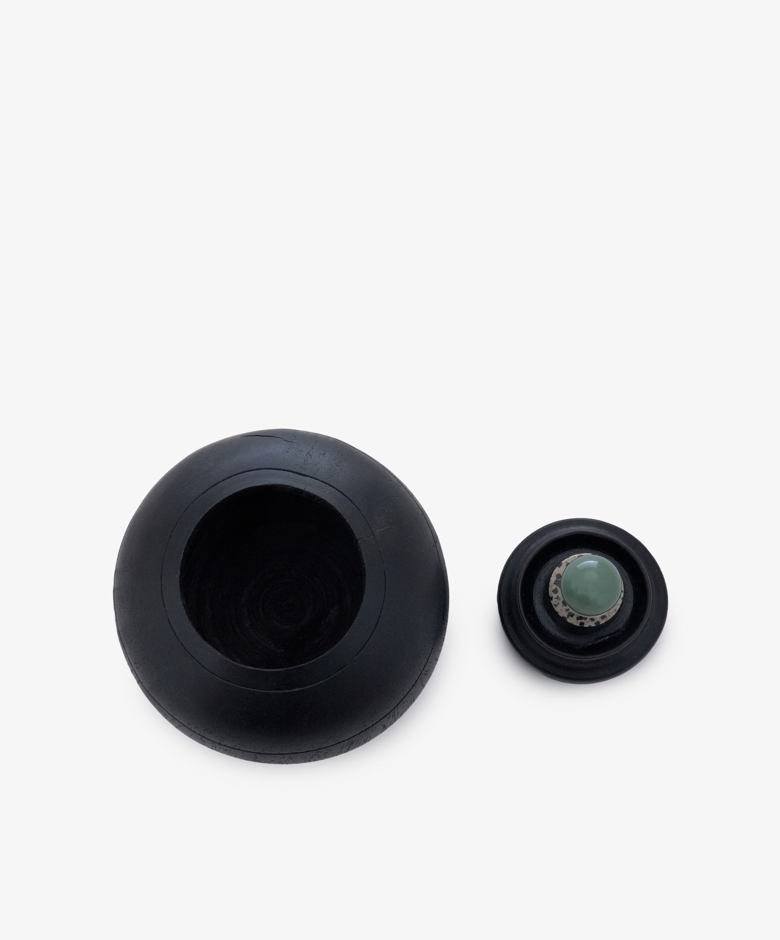 Two black spherical Curiosity Box 2 objects rest on a white background: one large, hollow with an open top; the other smaller, topped with a green circular cap.