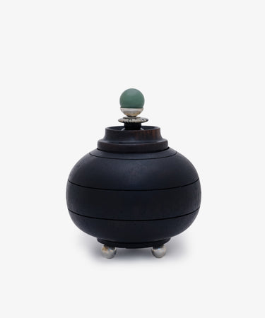 Curiosity Box 2: A round black African wood box with a lid, silver feet, and a green spherical handle on top, displayed against a plain white background.