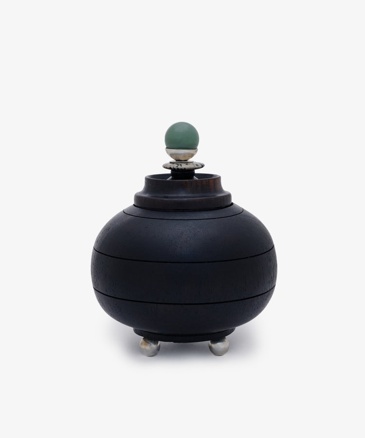 Curiosity Box 2: A round black African wood box with a lid, silver feet, and a green spherical handle on top, displayed against a plain white background.