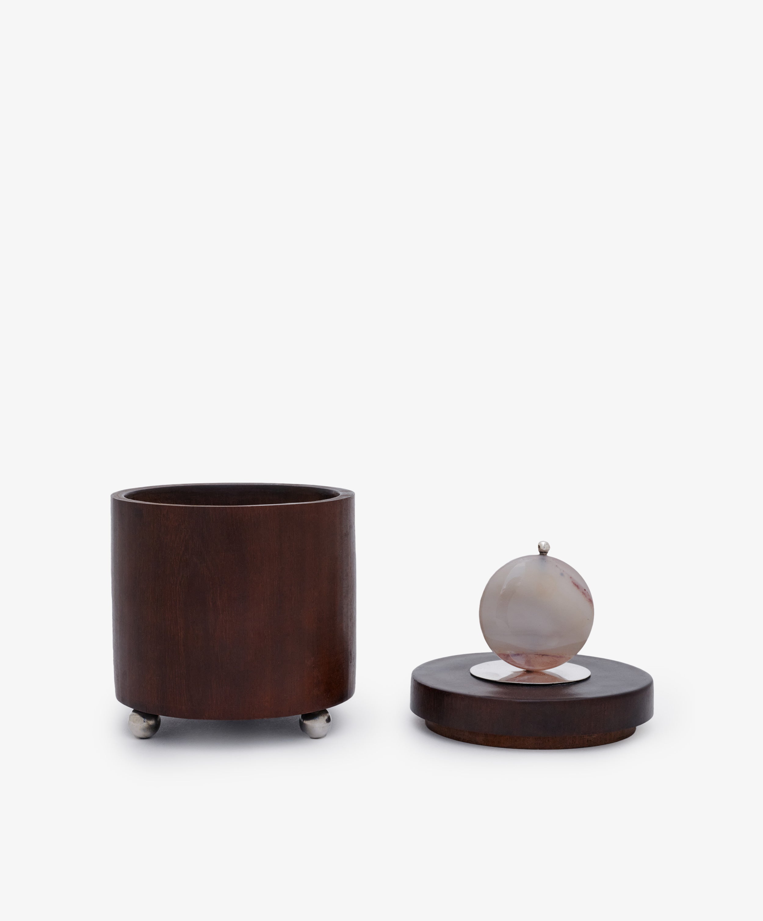 Curiosity Box 3: A cylindrical African wood box with a separate lid, round stone handle, and small metal feet—displayed on a white background. Ideal as a unique keepsake or art piece.