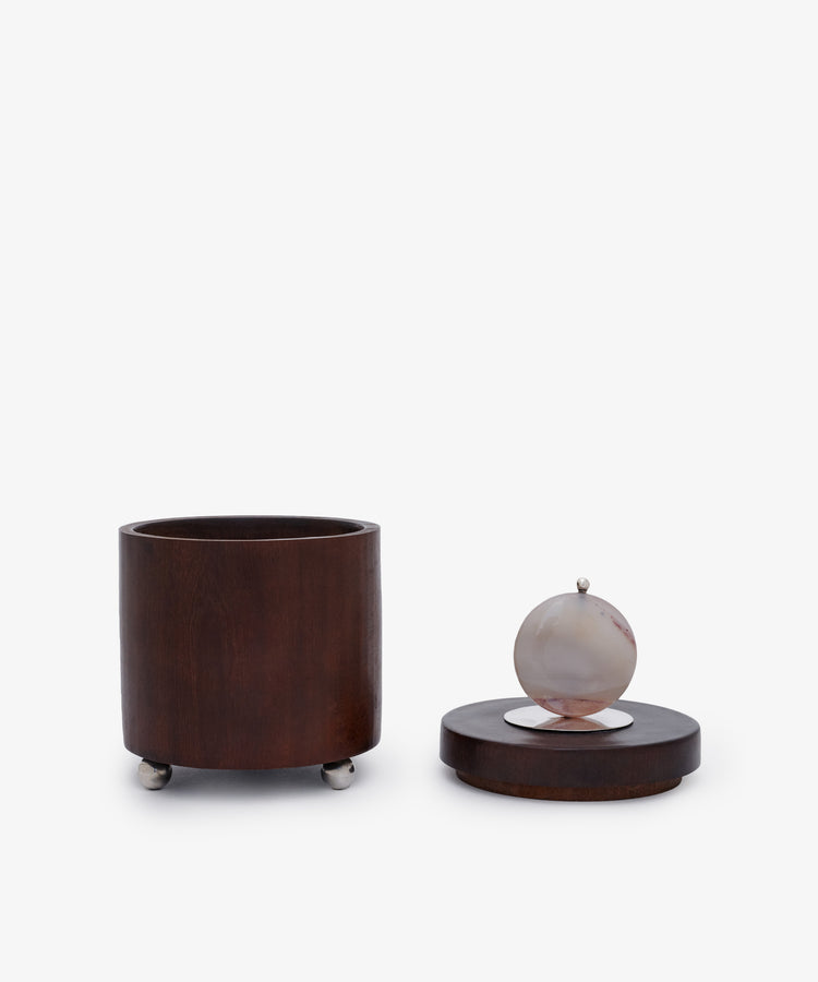 Curiosity Box 3: A cylindrical African wood box with a separate lid, round stone handle, and small metal feet—displayed on a white background. Ideal as a unique keepsake or art piece.
