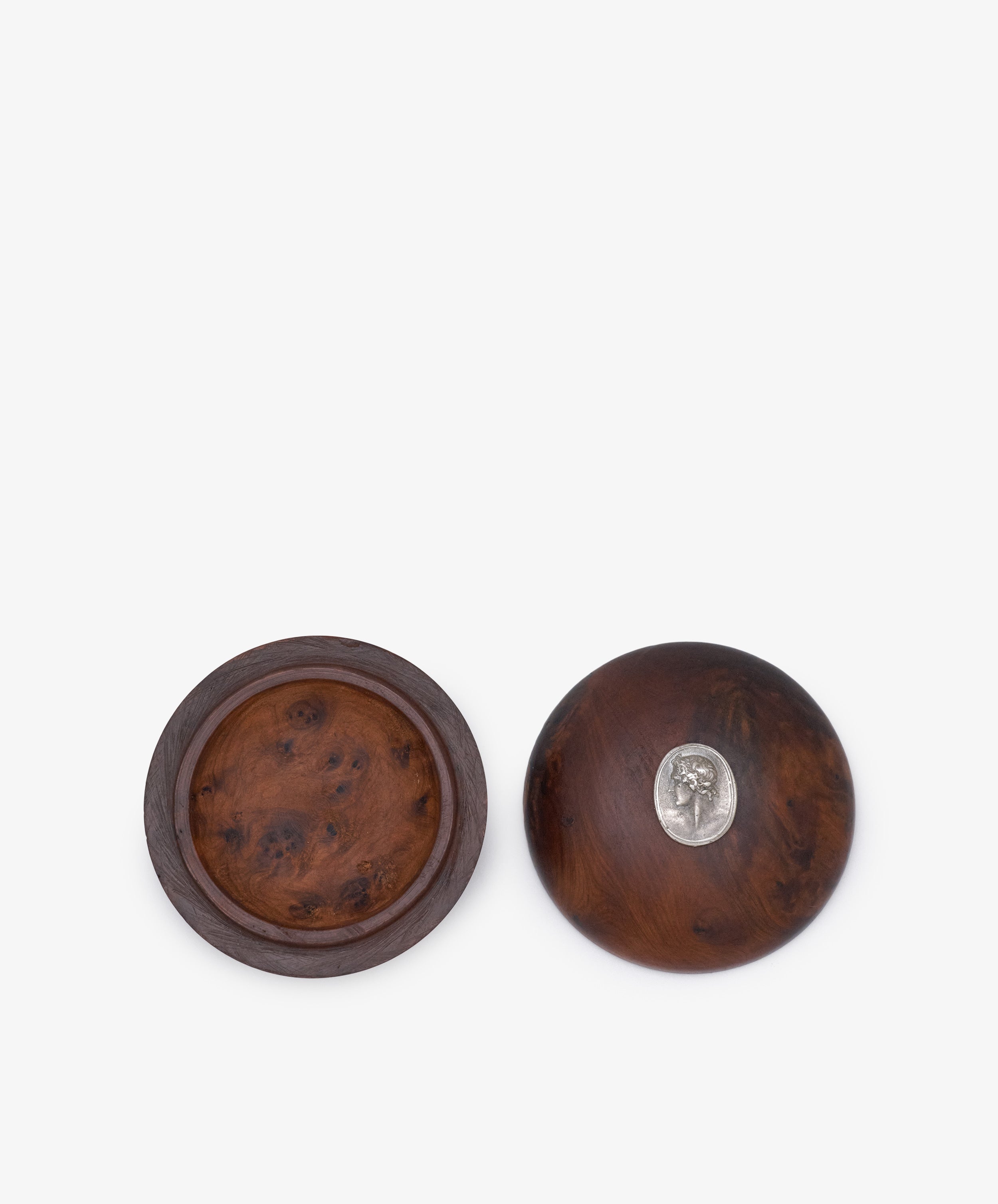 Curiosity Box 7: Set of two round African wood boxes with lids—one open to reveal the interior, the other adorned with a small metal emblem. A distinctive keepsake art box for your treasured items.