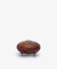 Curiosity Box 7: Small round African wood box with lid, silver knob, and three silver legs. An elegant keepsake art piece photographed against a plain white background.