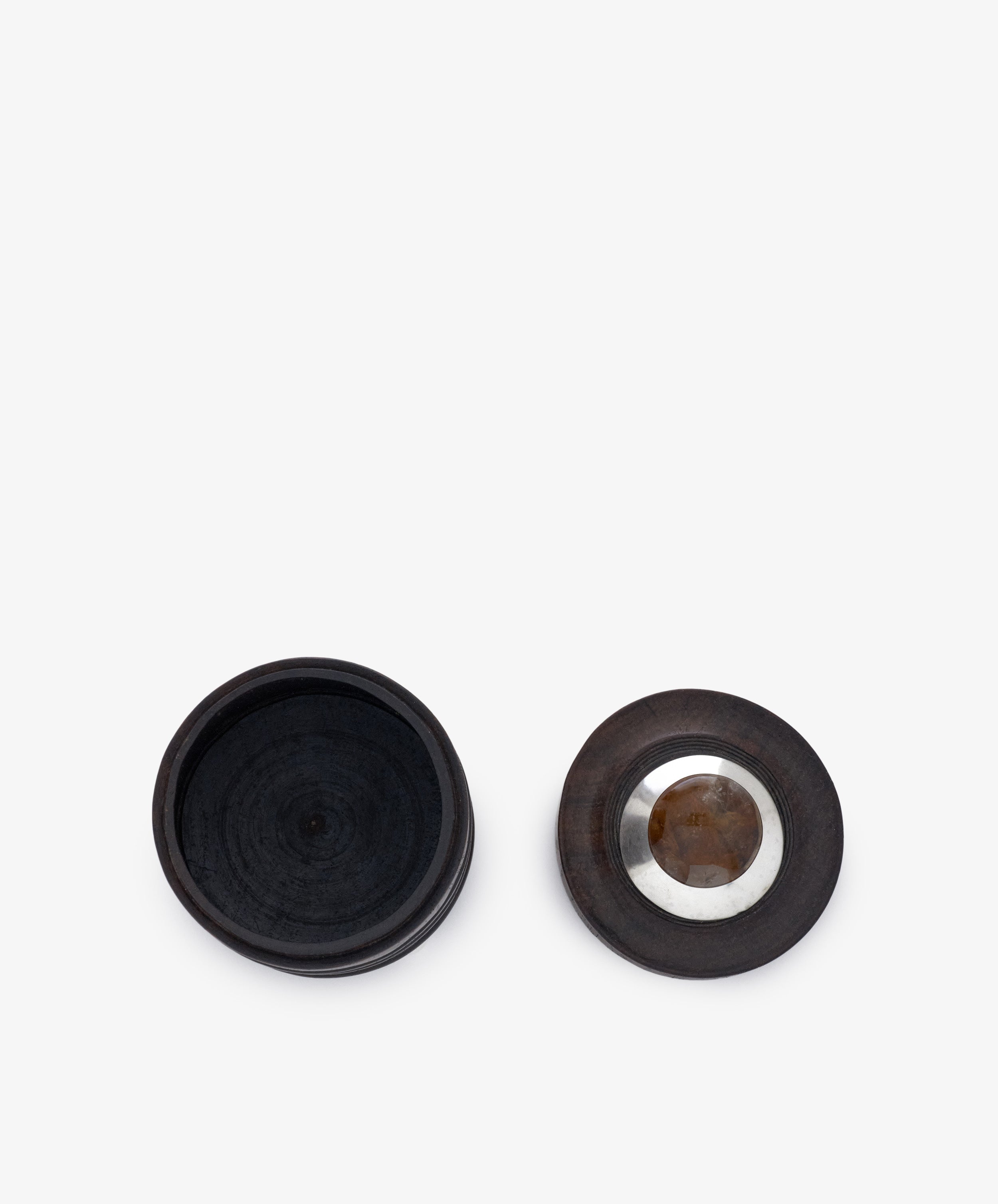 The Curiosity Box 8 is a round African wood box shown open, with its lid—featuring a striking metal and stone inlay at the center—placed to the right.